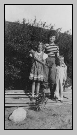 Adrienne Deloris Terry standing by plumb bushes behind ranch house