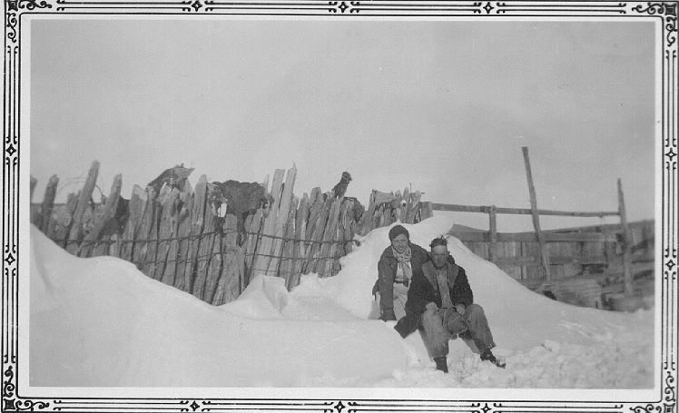 <johnie and adron posed in a snow bank with a post corral backdrop>