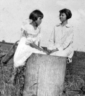 <pauline and pearl downer sitting in metal tank hand plow cultivator in the background>