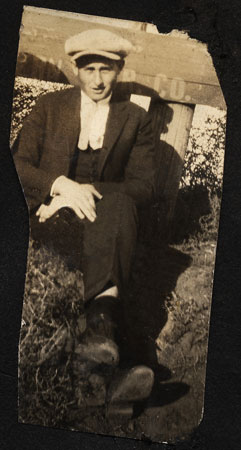 <man sitting by a road sign wearing a golf style cap  ivy cap flat cap>