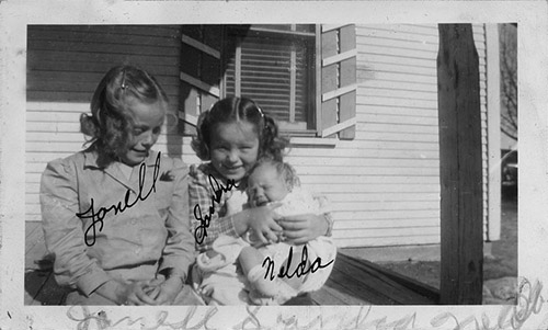 <sandra holding nelda front porch of farm house>