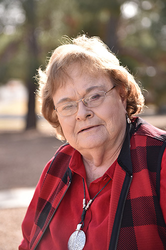 janell portait on patio red plad vest